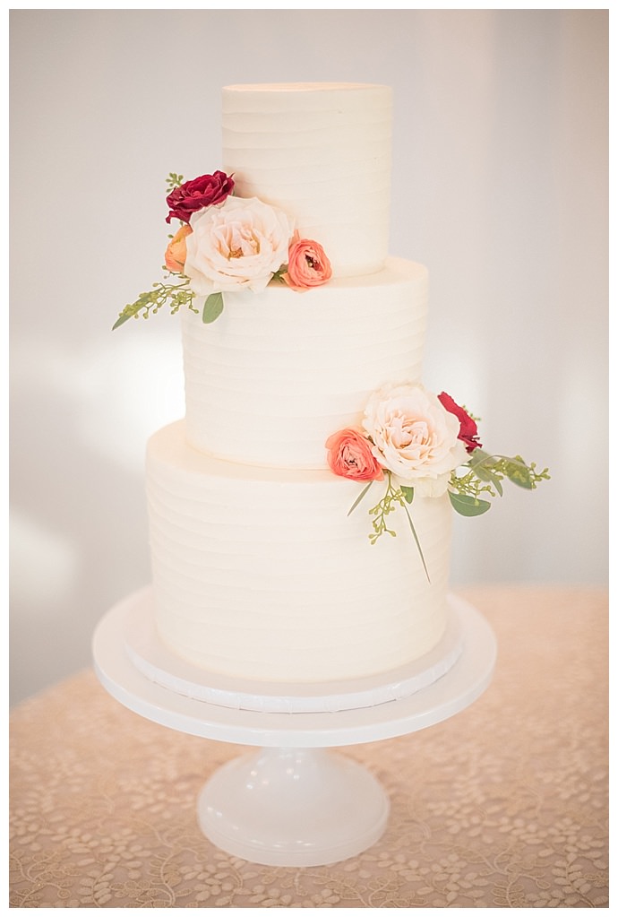 white-three-tiered-wedding-cake-pink-and-peach-flowers-mikkel-paige-photography