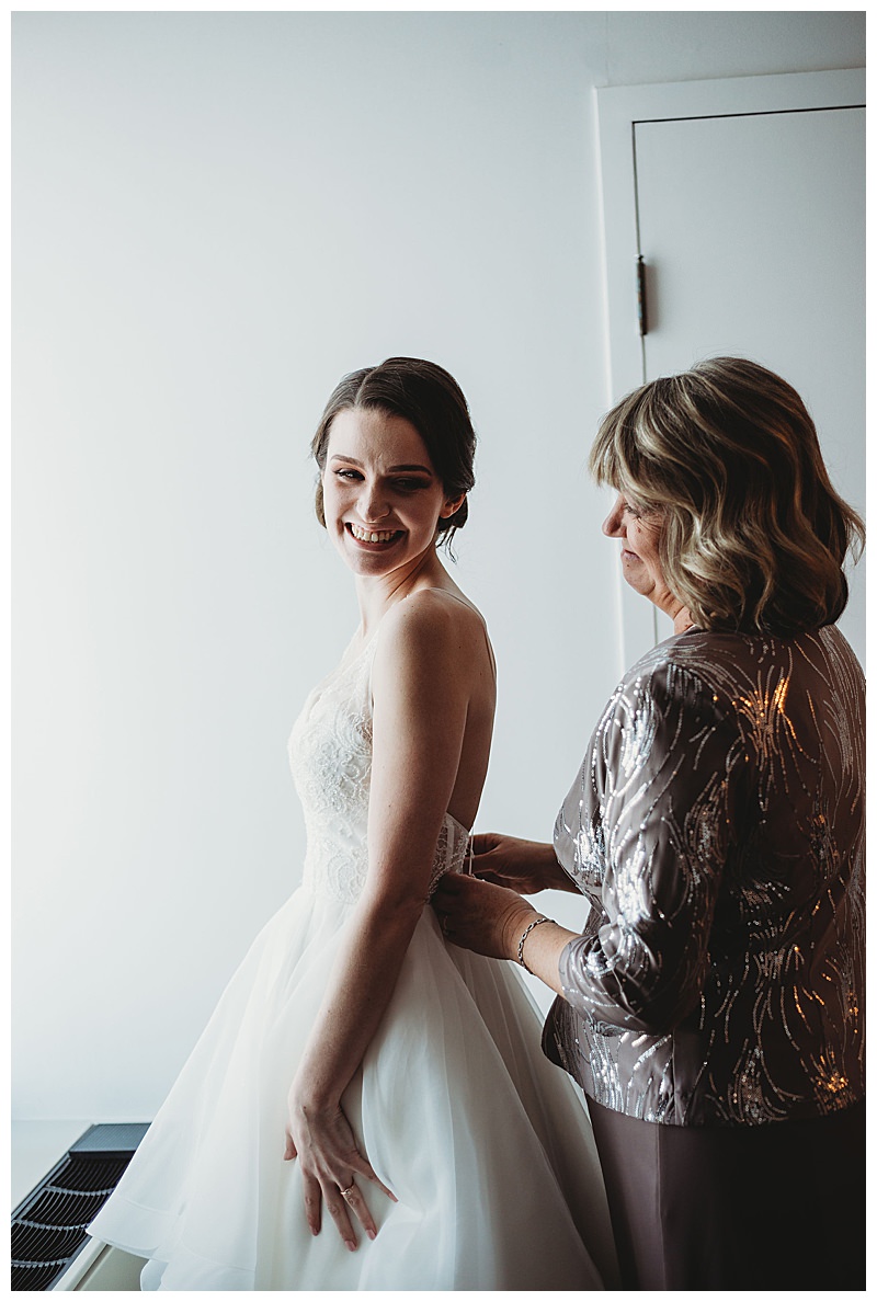 mother-putting-on-daughters-wedding-dress