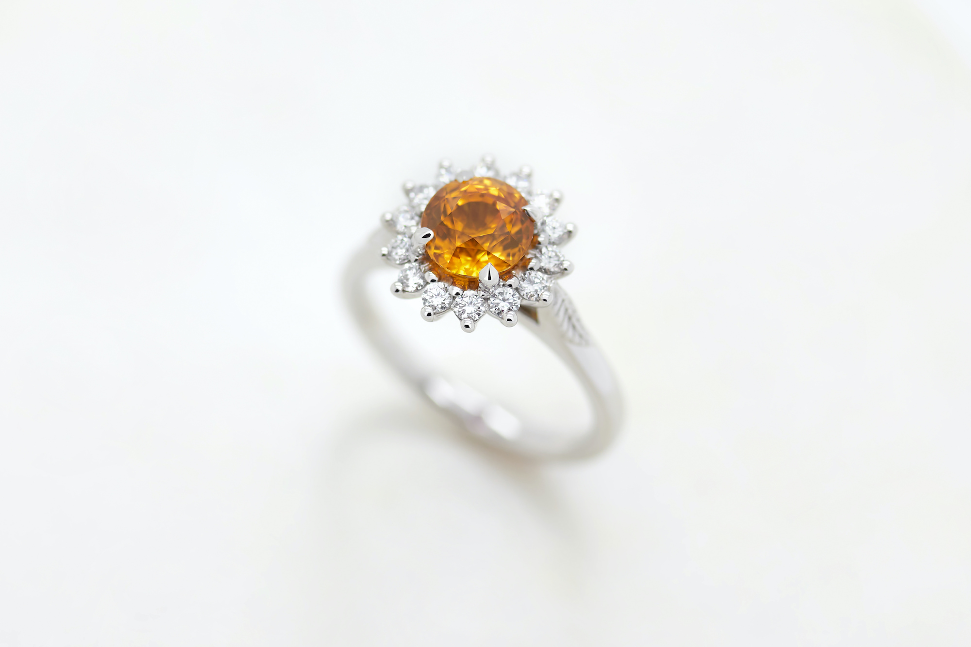 Orange sapphire engagement ring with diamond halo