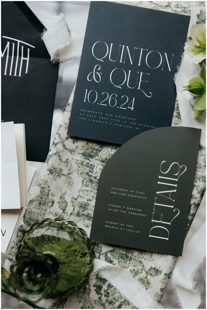 Black wedding invitation set on green fabric
