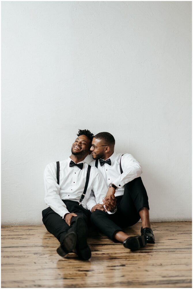Couple in formal wear sitting on floor, smiling.