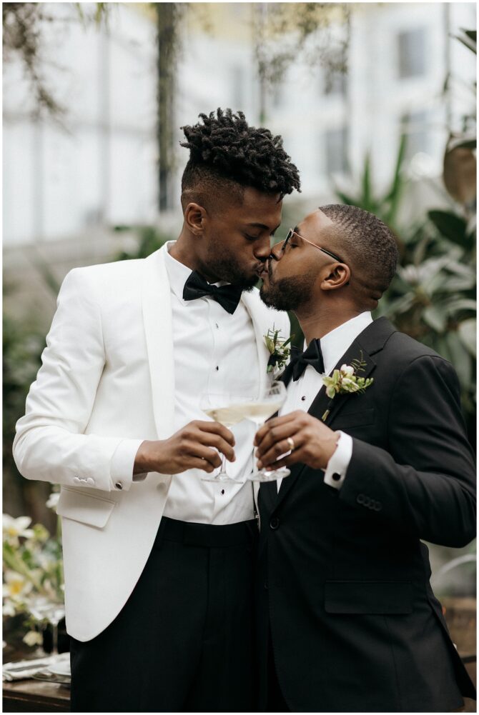 Couple kissing at wedding, holding champagne glasses.
