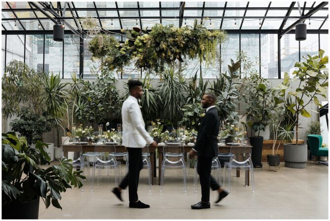 Two men walking in a lush, modern greenhouse setting.