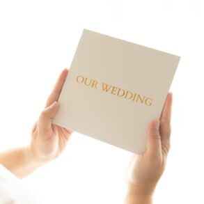 Person holding 'Our Wedding' invitation card