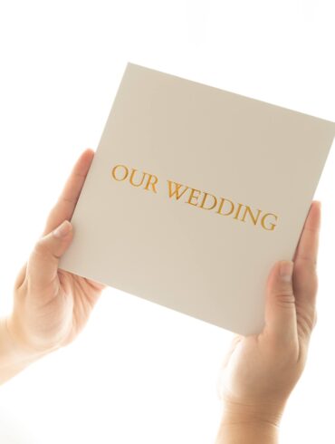 Person holding 'Our Wedding' invitation card