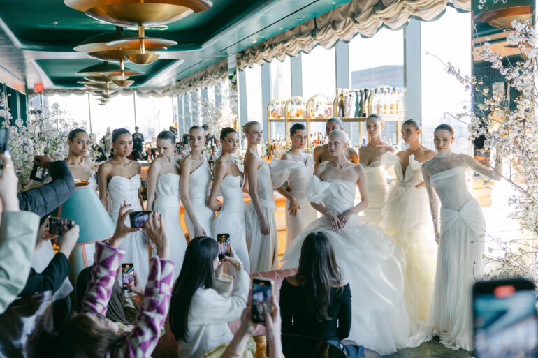 Models in white wedding dresses posing at event.