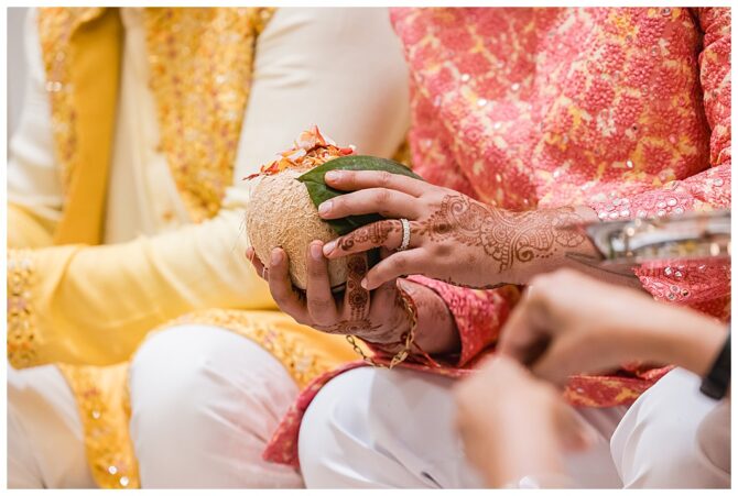 Henna hands holding decorative coconut ceremony.