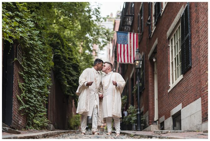 Couple kissing on charming cobblestone street with flag.