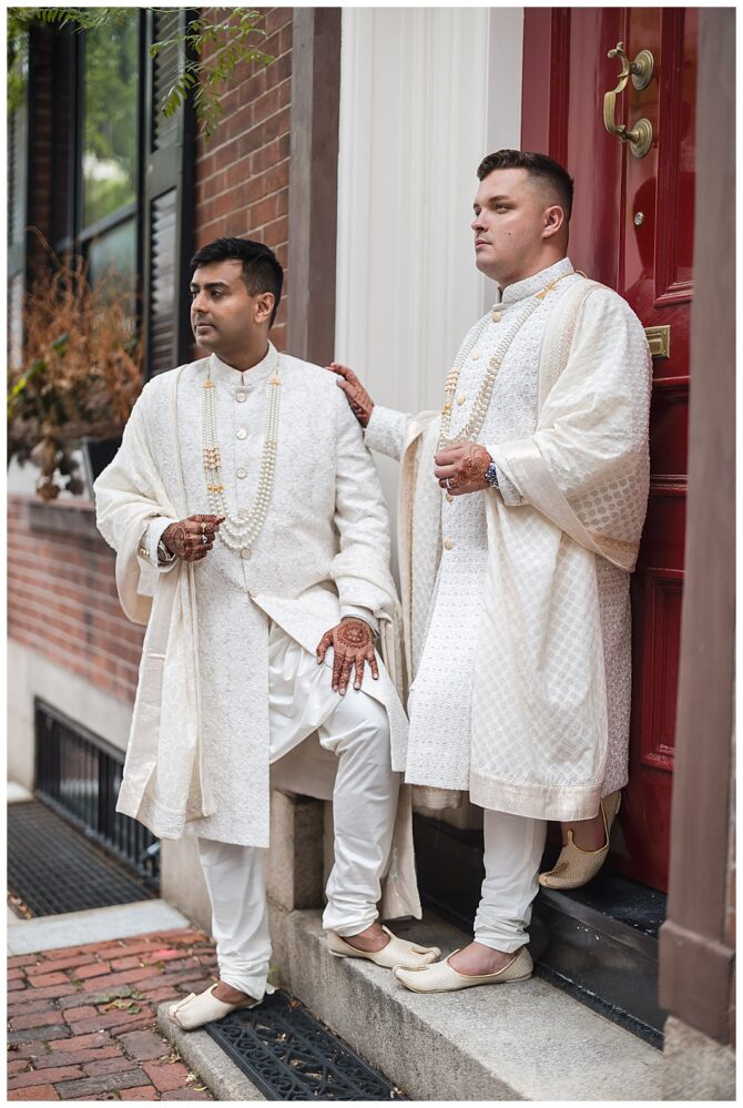 Two men in traditional white attire pose outside.