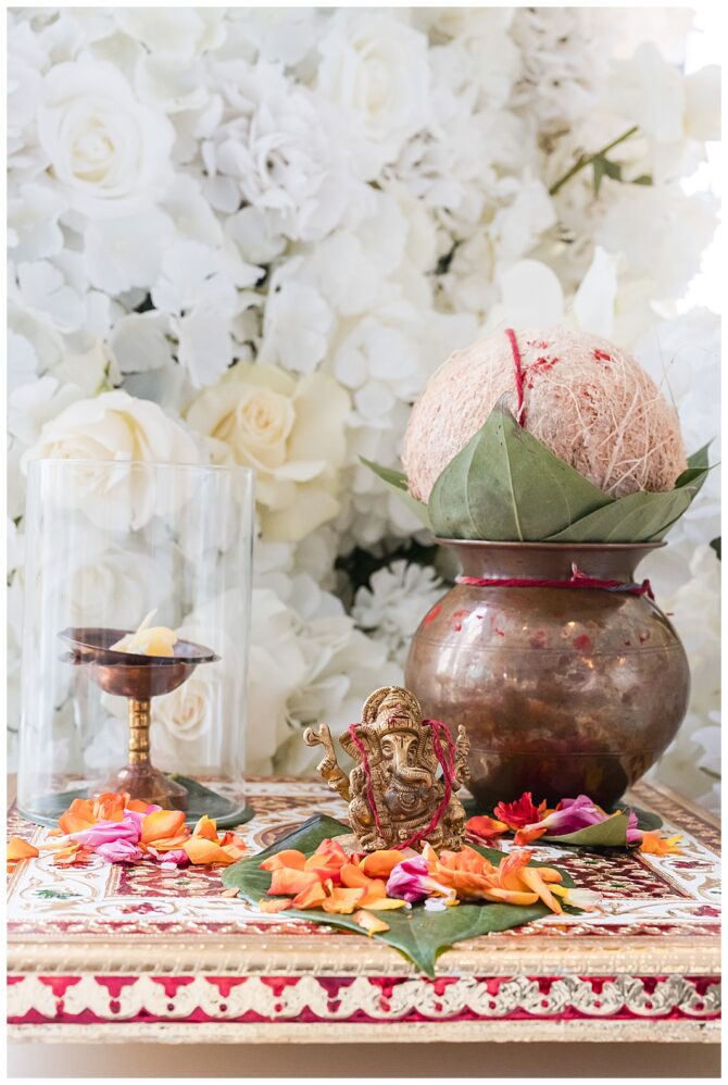 Traditional Hindu altar with Ganesha, flowers, and coconut.