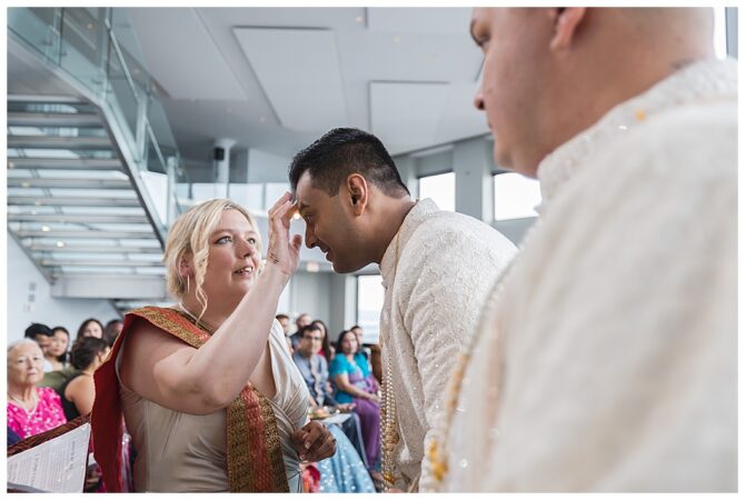 Woman applying mark on man's forehead during ceremony.