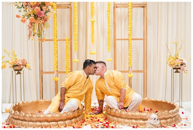 Couple in yellow traditional attire kissing in ceremony.
