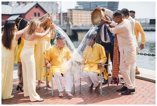 Men in yellow drenched with water in celebration.