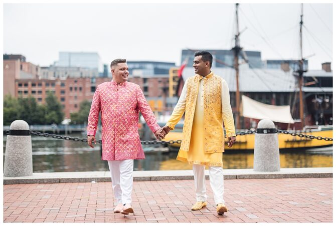 Couple in colorful attire holding hands by waterfront.