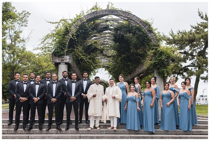 Wedding party in blue dresses and suits outside.