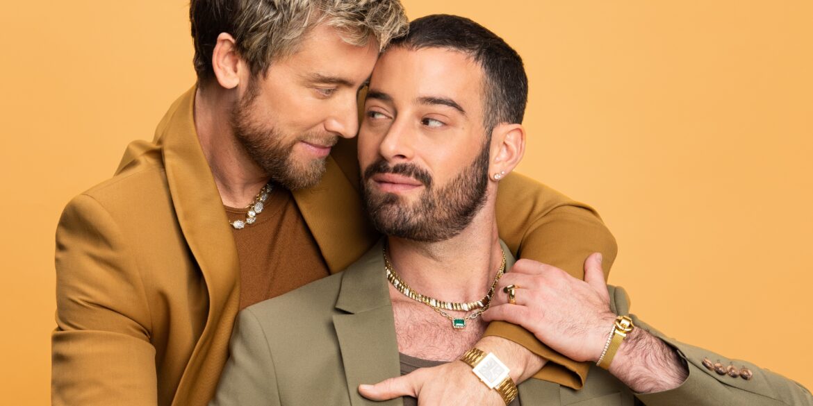 Two men in stylish suits embrace warmly.