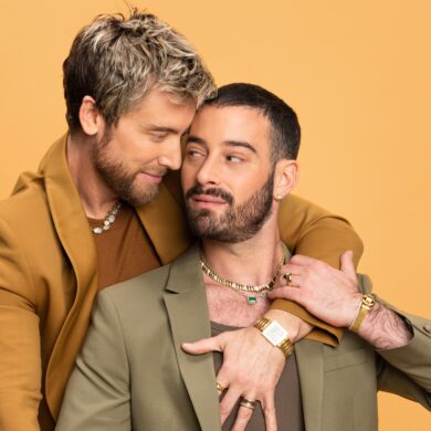 Two men in stylish suits embrace warmly.