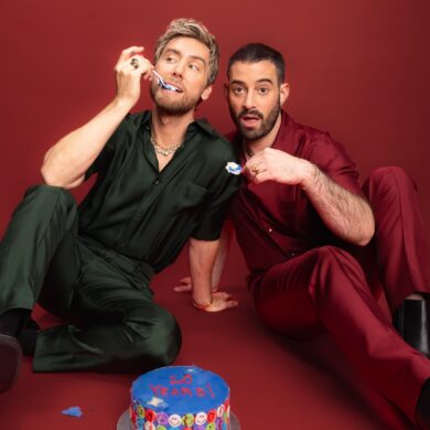 Two people in colorful outfits with a cake.