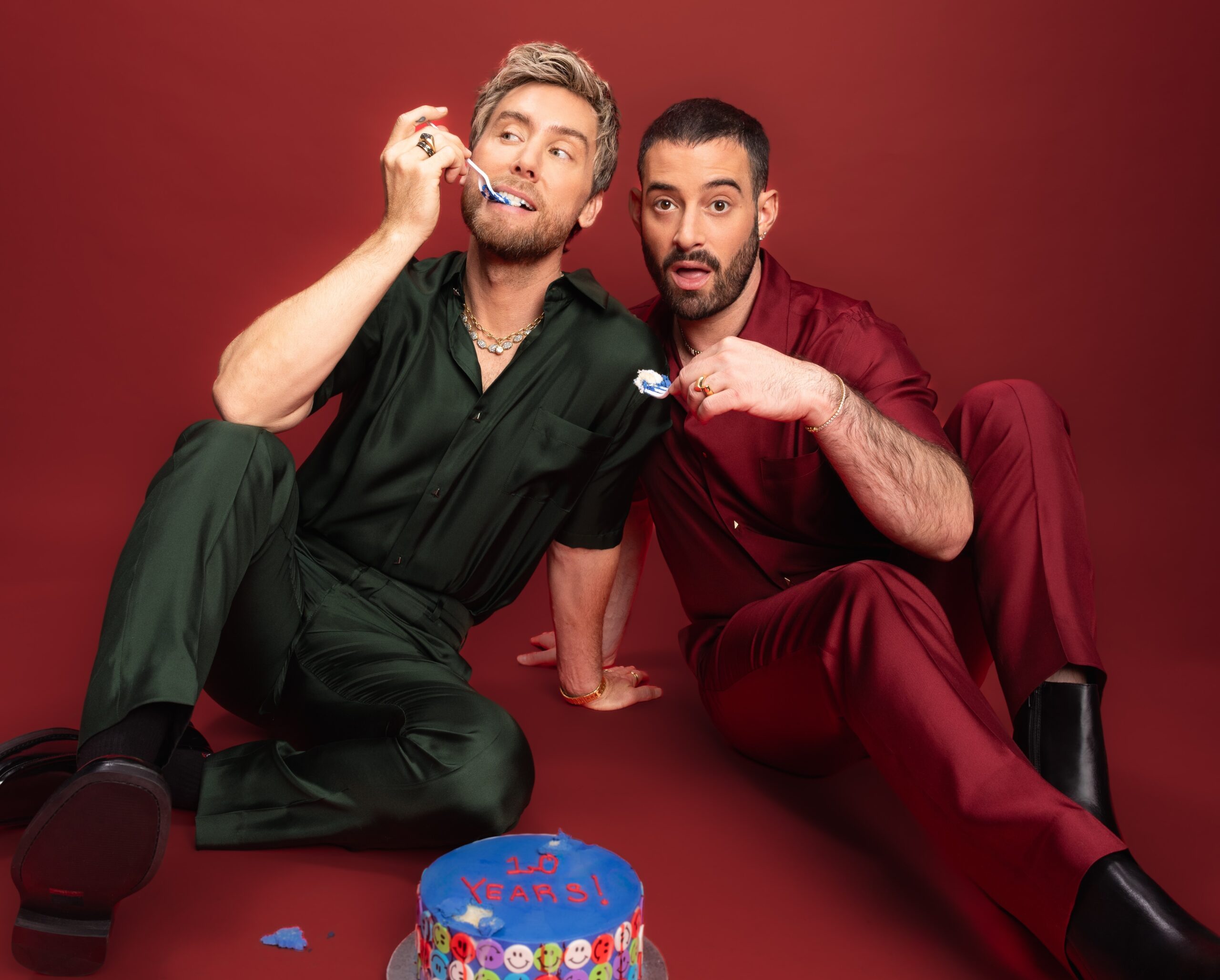 Two people in colorful outfits with a cake.