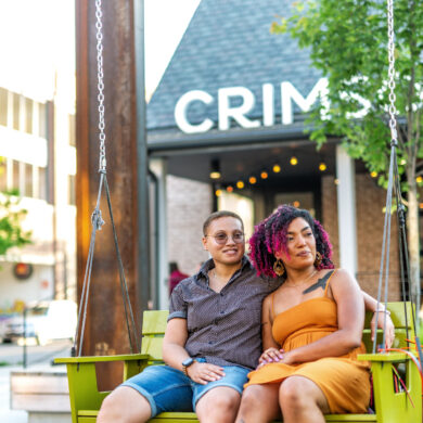 Couple sitting on swing outside cafe.