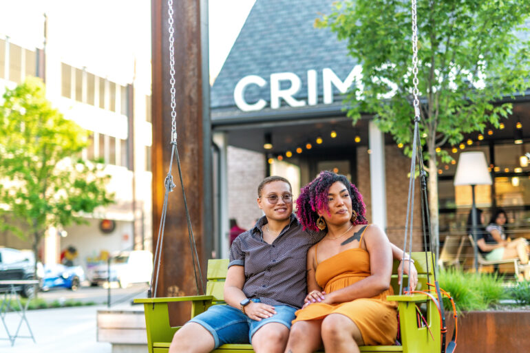 Couple sitting on swing outside cafe.
