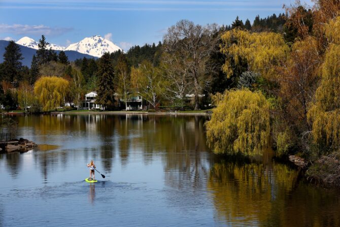 Person paddleboarding on lake with mountain view.