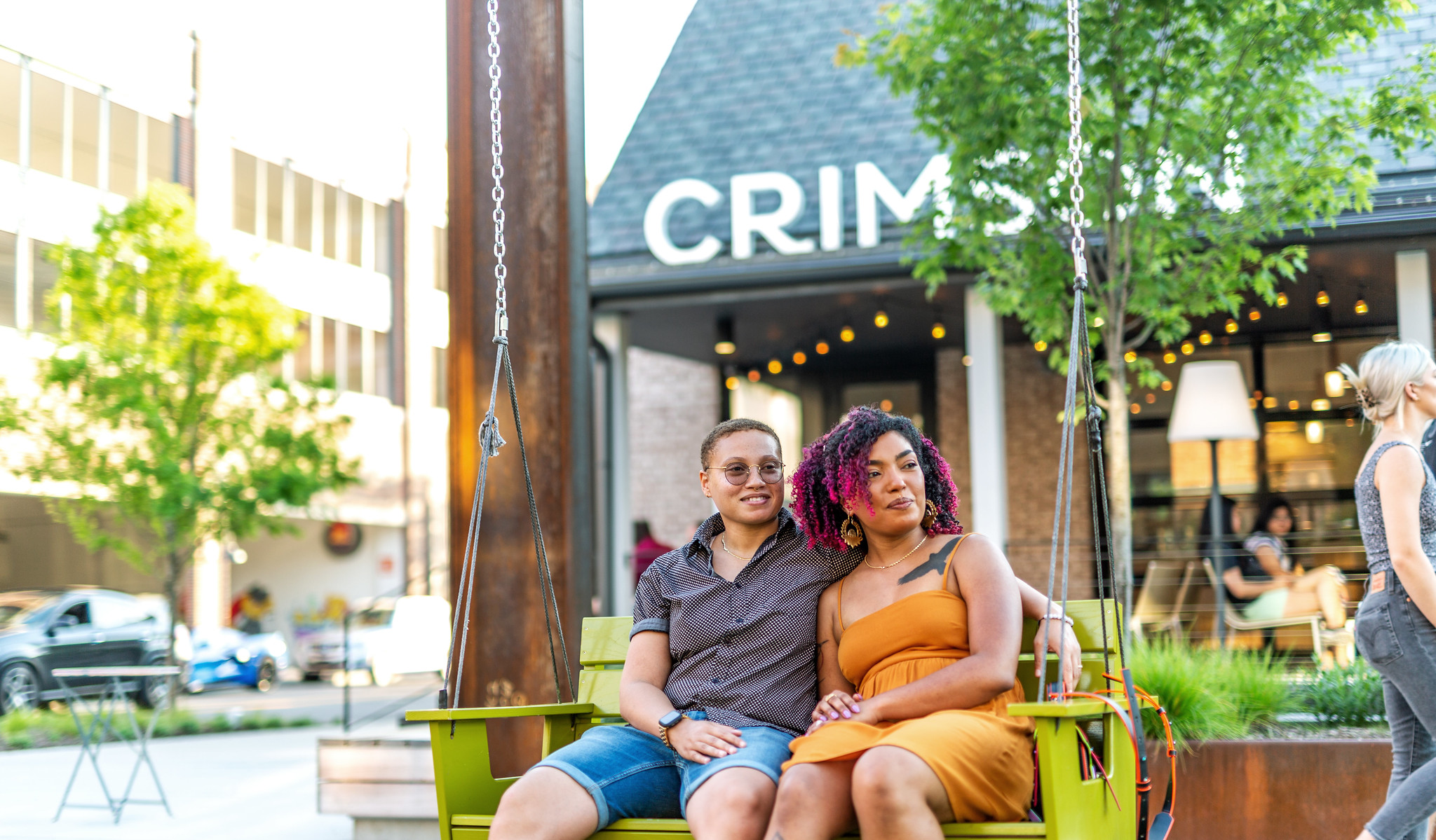 Couple sitting on swing outside cafe.