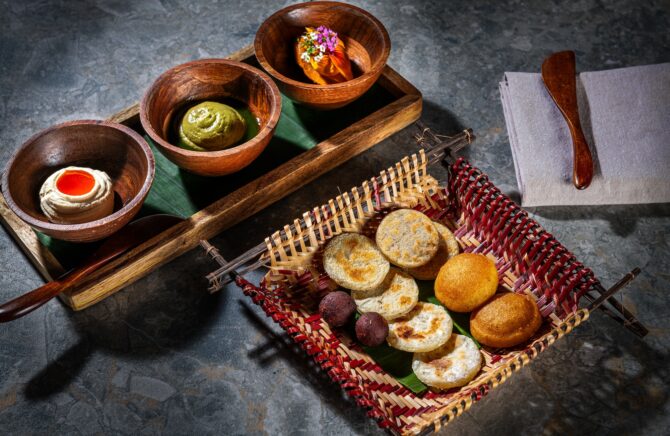 Assorted breads and spreads in wooden bowls.