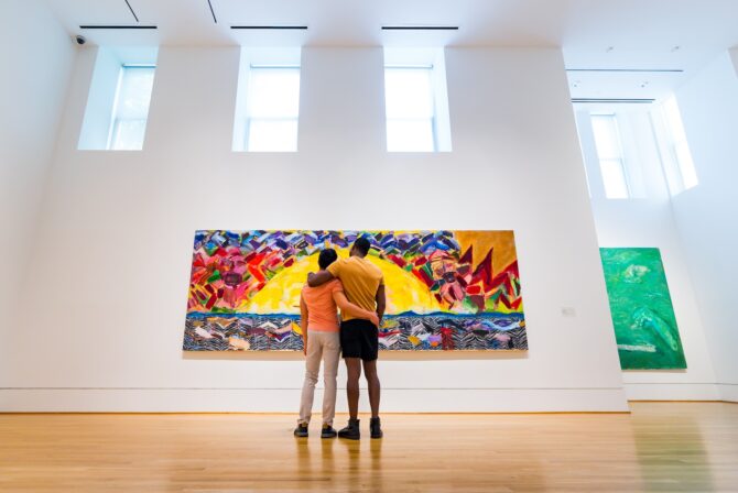 Couple admiring colorful abstract painting in gallery.