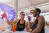 Two friends with fans enjoying drinks at a cafe.