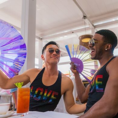 Two friends with fans enjoying drinks at a cafe.