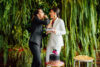 Two women sharing cake, surrounded by greenery.
