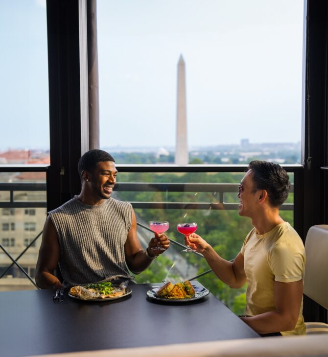 Two friends toasting at rooftop restaurant, Washington Monument.